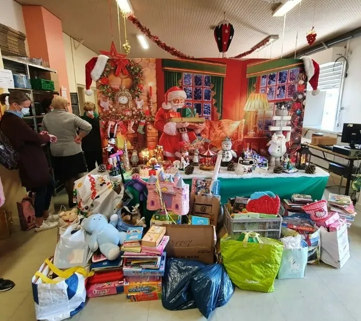 Bénévoles devant un stand de jouets collectés pour les Restos du Cœur, décor de Noël, 3/3